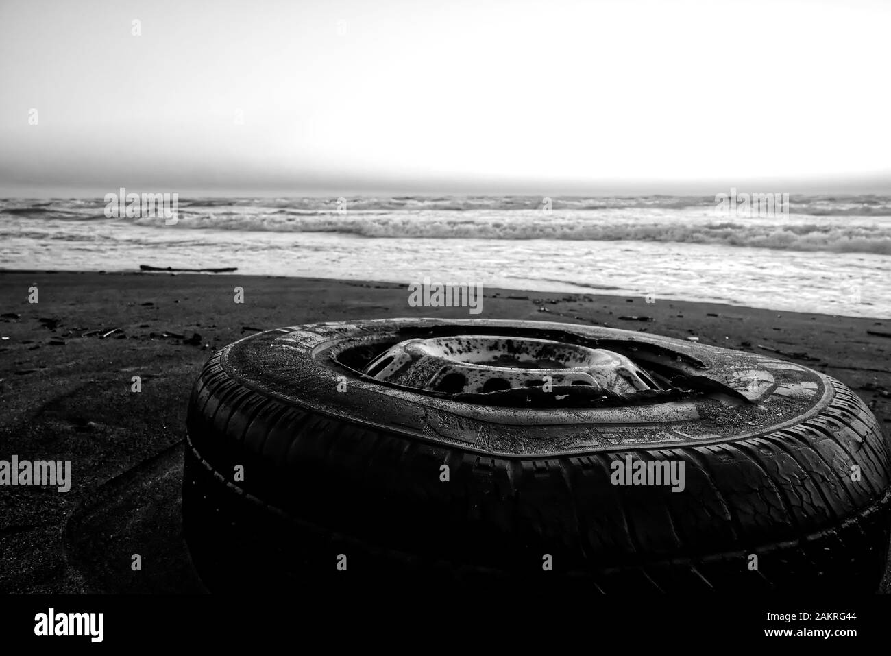 Ein alter Reifen an einem Strand zeigt die Auswirkungen auf die Natur der menschlichen Verschmutzung Stockfoto