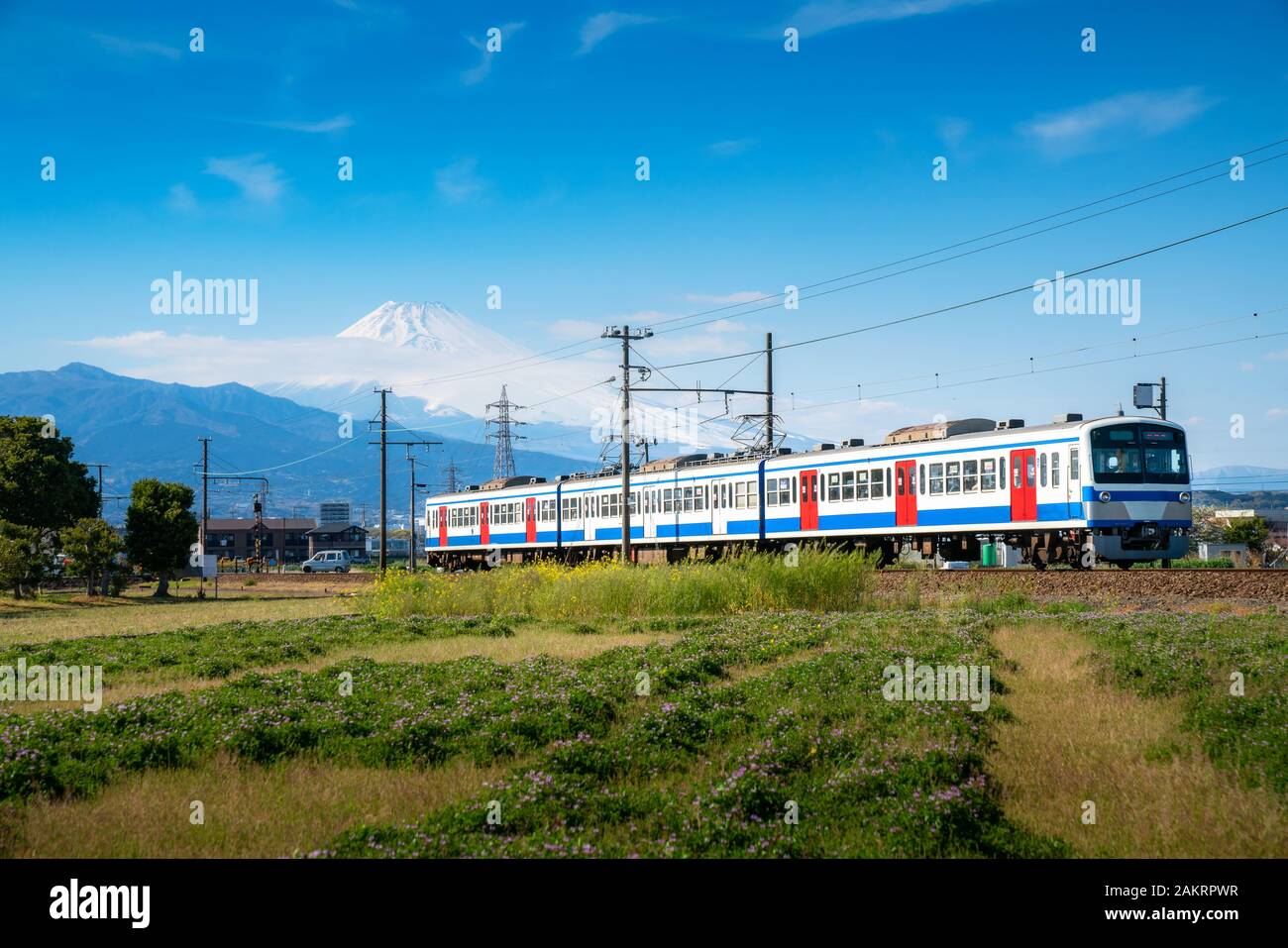 Ein Zug der JR Izuhakone Tetsudo-Sunzu Line reisen durch die Landschaft an einem sonnigen Frühlingstag und Mt. Fuji in Mishima, Shizuoka, Japan. Rai Stockfoto
