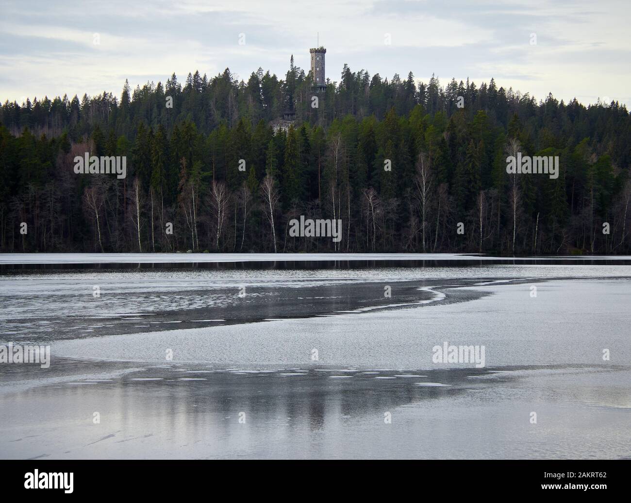 Späte Herbstlandschaft im finnischen Naturpark Aulanko. Spiegelung der Szene und des Aussichtsturms im stillenden und eisigen Wasser des Aulangonjarvi Stockfoto