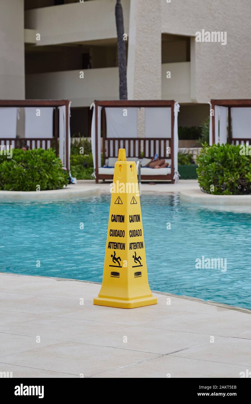 Ein Warnschild am Rand eines Schwimmbads, das auf eine rutschige Oberfläche warnt. Stockfoto