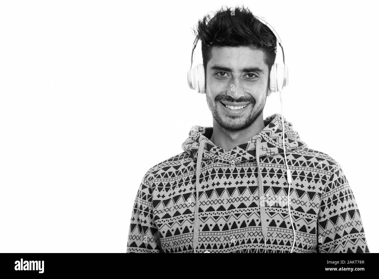 Studio shot der Jungen glücklich Persischen Mann lächelnd, während Sie Musik hören Stockfoto