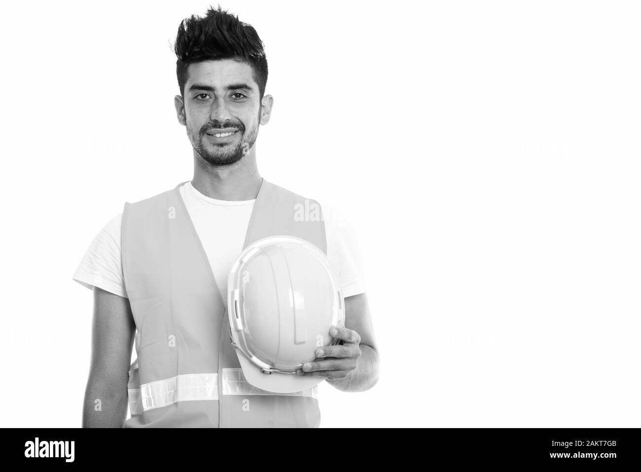 Studio shot der Jungen glücklich Persischen mann Bauarbeiter lächelnd, während sie Schutzhelm Stockfoto