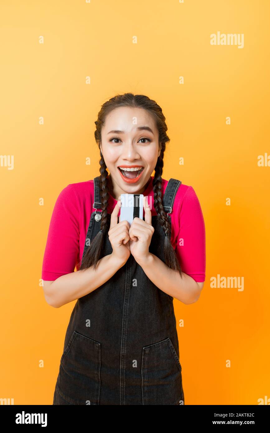 Junge lächelnde schöne asiatische Frau mit Kreditkarte in der Hand zeigen, Vertrauen und Zuversicht für eine Zahlung. Stockfoto