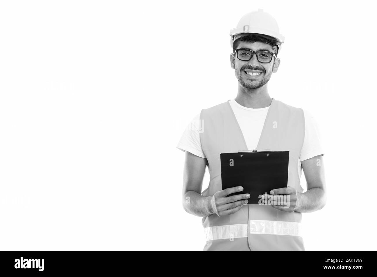 Studio shot der Jungen glücklich Persischen mann Bauarbeiter lächelnd, während Sie die Zwischenablage Stockfoto