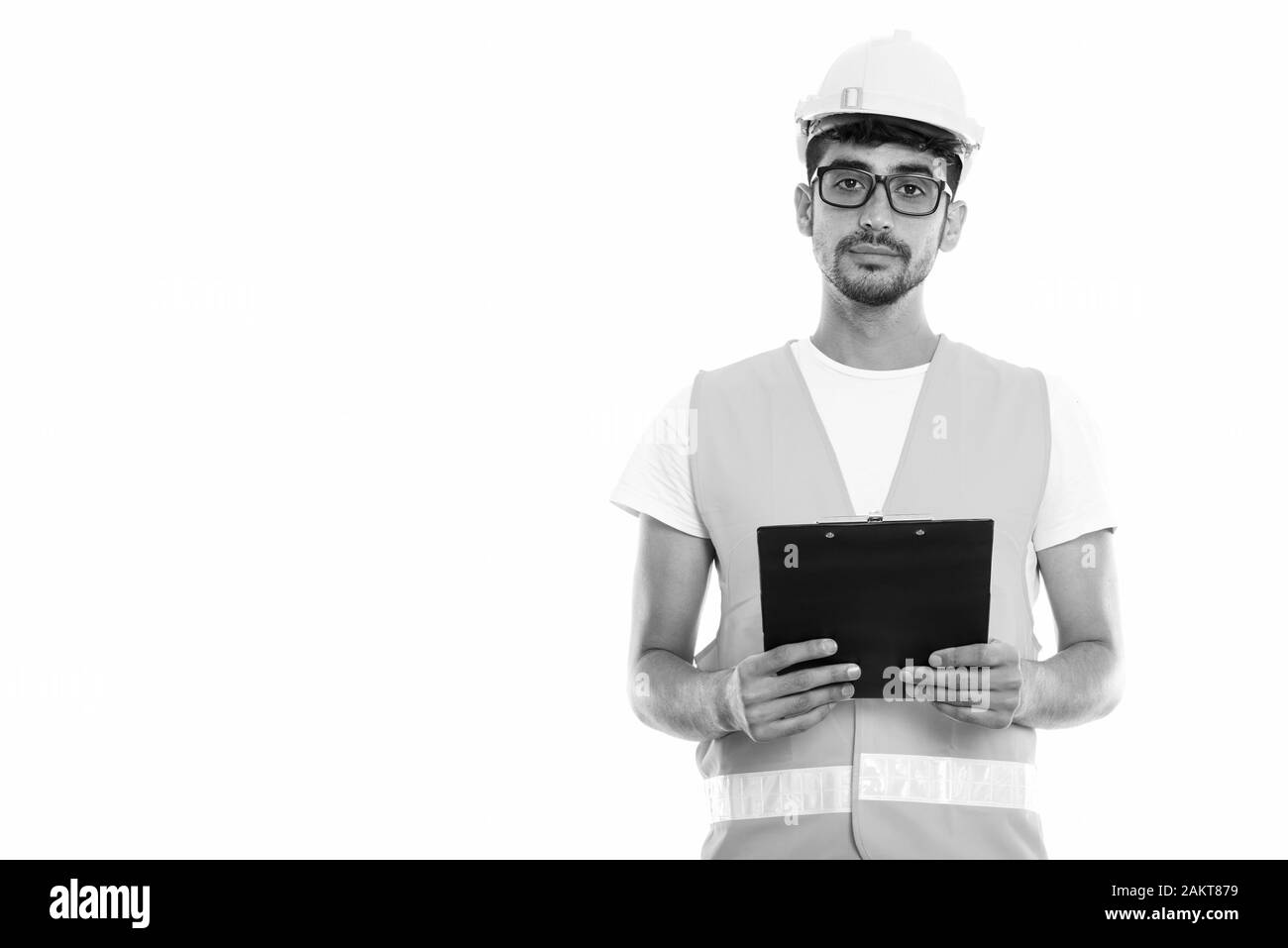 Studio shot der jungen Persischen mann Bauarbeiter holding Zwischenablage beim Tragen von Brillen Stockfoto