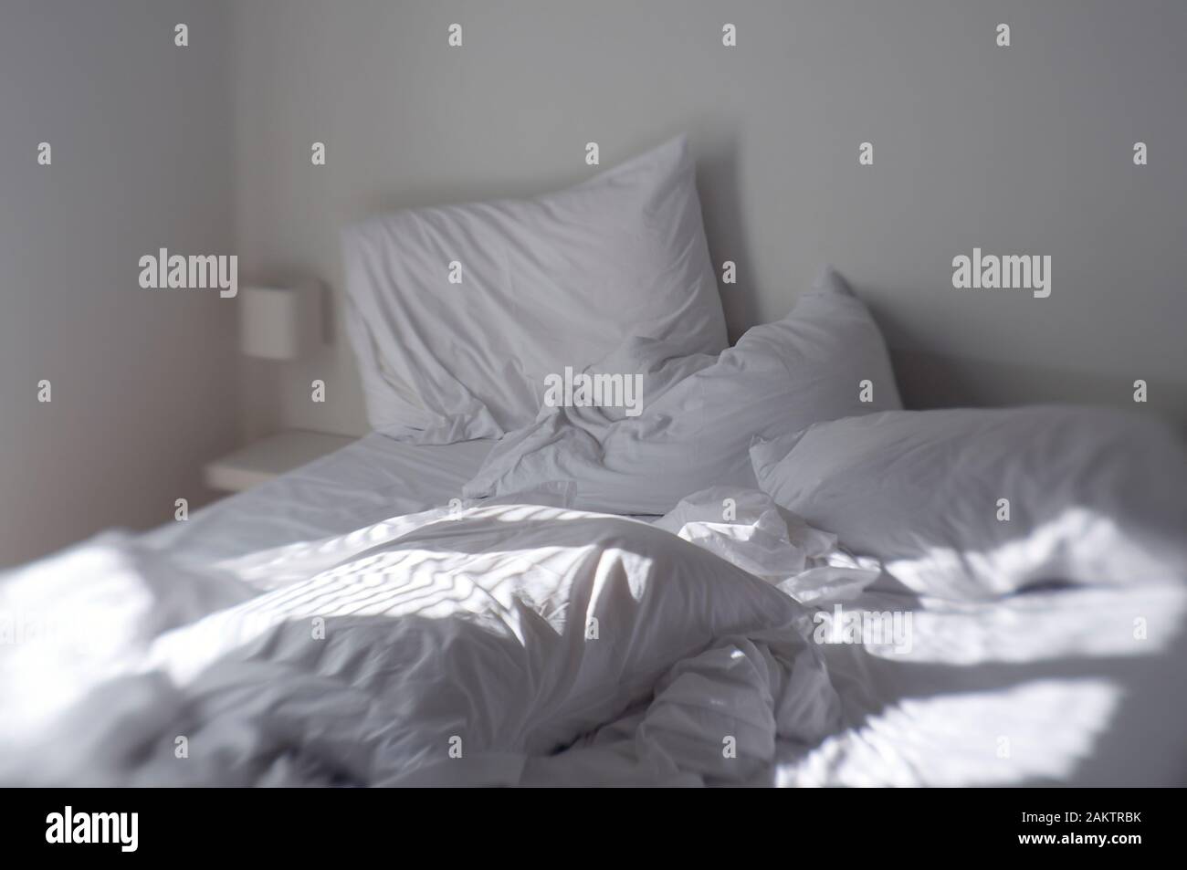 Tilt-shift Blick auf Morgen Sun Streaming über Rumpled Blätter und verbeult Kissen eines gut geschlafen - im Bett Stockfoto