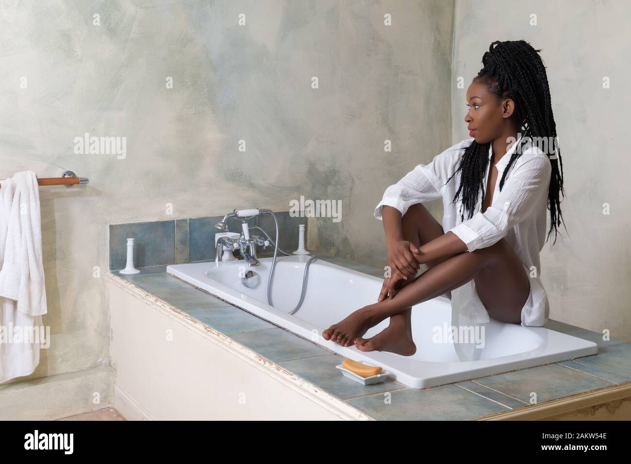 Junge Frau mit Afro Frisur Vorbereitung einer Badewanne in einem Vintage White Bad zu nehmen Stockfoto