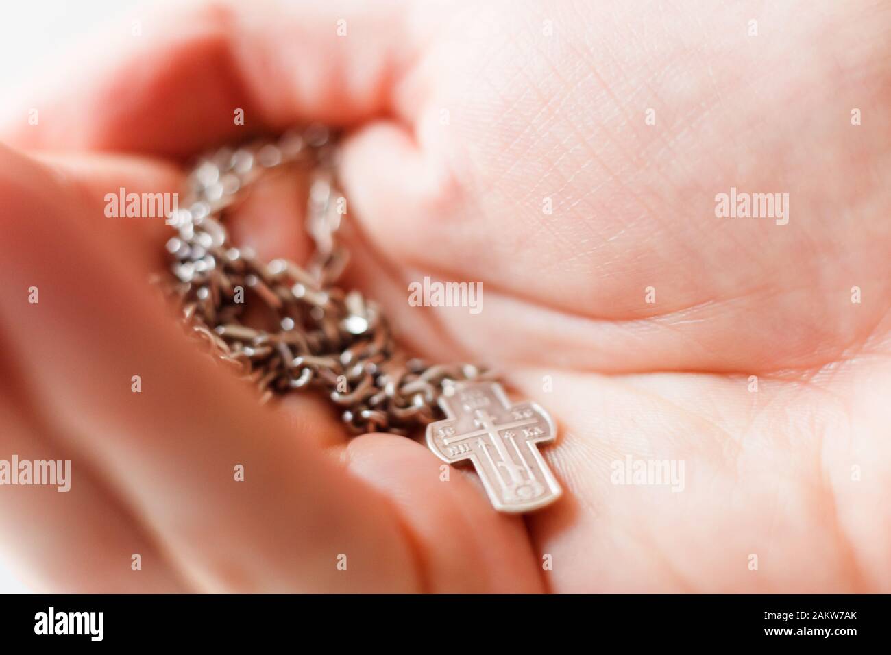 Silber Kreuz in der Hand mit Fokus auf das Kreuz, flacher DOF Stockfoto