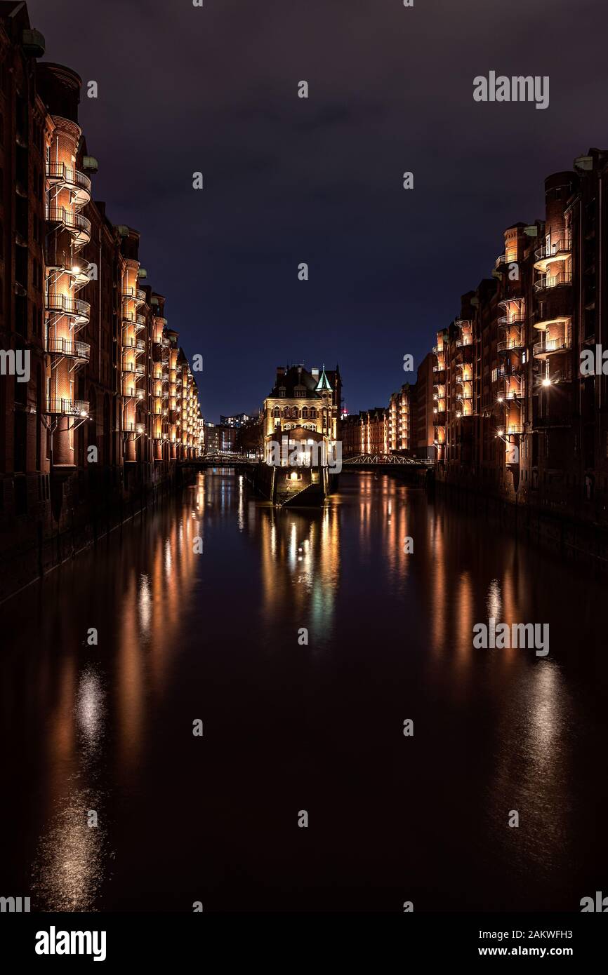 Beleuchtete Wasserschloss (Wasserschloss - berühmtes historisches Gebäude) in der Speicherstadt (Lagerviertel) Hamburg nach Sonnenuntergang während der blauen Stunde Stockfoto