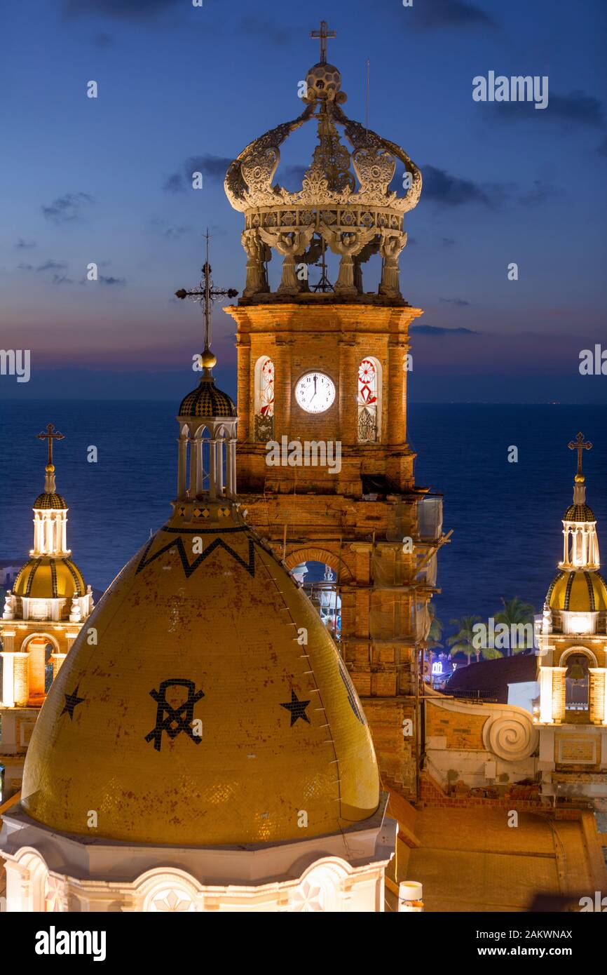 Mexiko, Puerto Vallarta, Jalisco, Kirche Unserer Lieben Frau von Guadalupe leuchtet in der Dämmerung mit dem Glockenturm und Kuppel Stockfoto
