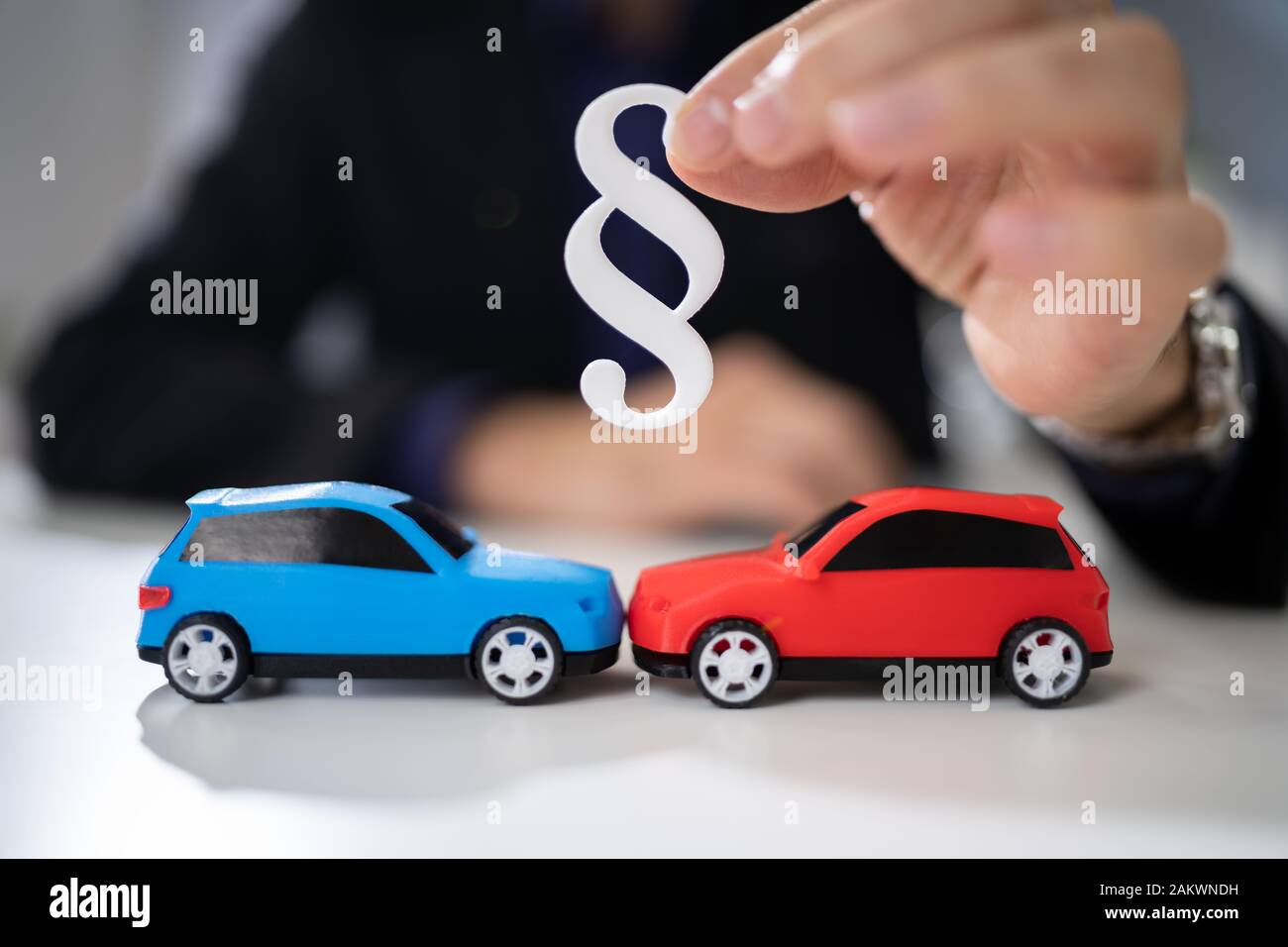 Rechtsanwalt hält zwei kleine Autos in der Hand und Absatz Zeichen Stockfoto