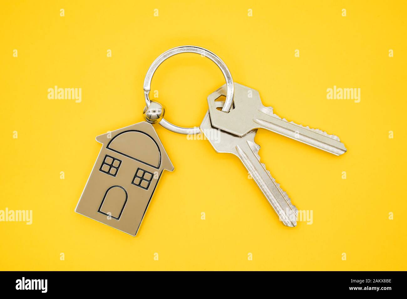 Schlüsselanhänger mit Haus Symbol und Tasten auf gelben Hintergrund, Immobilien Konzept Stockfoto