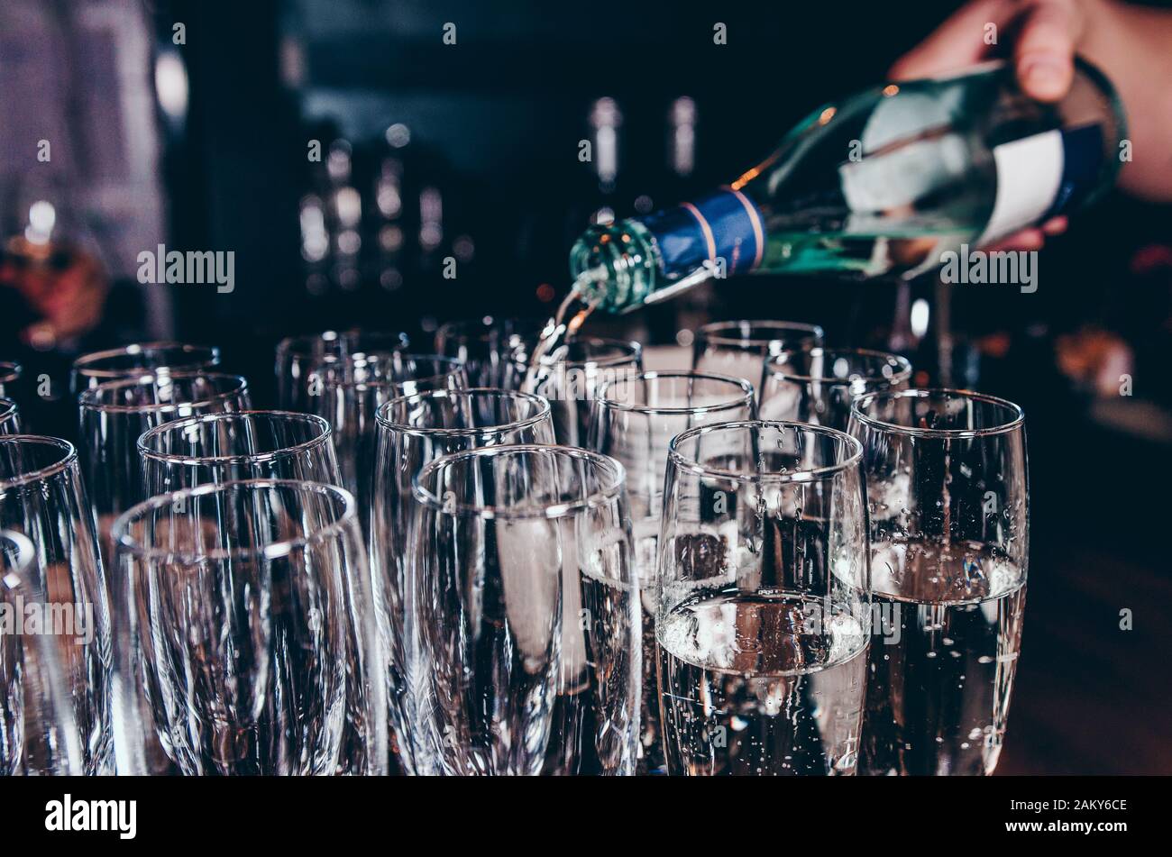 Barkeeper, der Champagner in Weingläser auf dem Tisch gießt Stockfoto