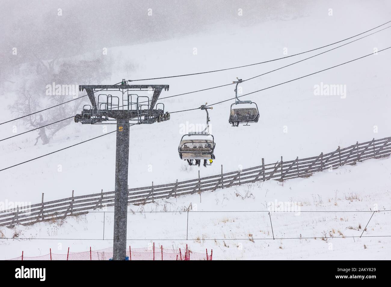 Menschen, die im Schneefall eine Seilbahn bergab klettern Stockfoto