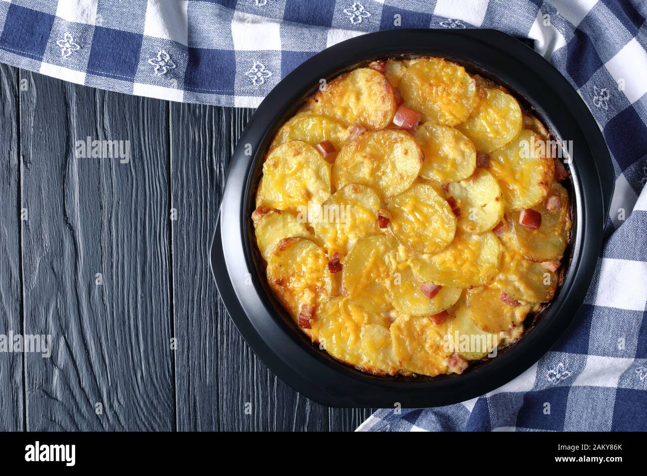 Nahaufnahme EINER köstlichen, kitschigen, cremigen Kartoffelchasserole mit geräuchertem Ham in einer Backform, horizontaler Blick von oben Stockfoto