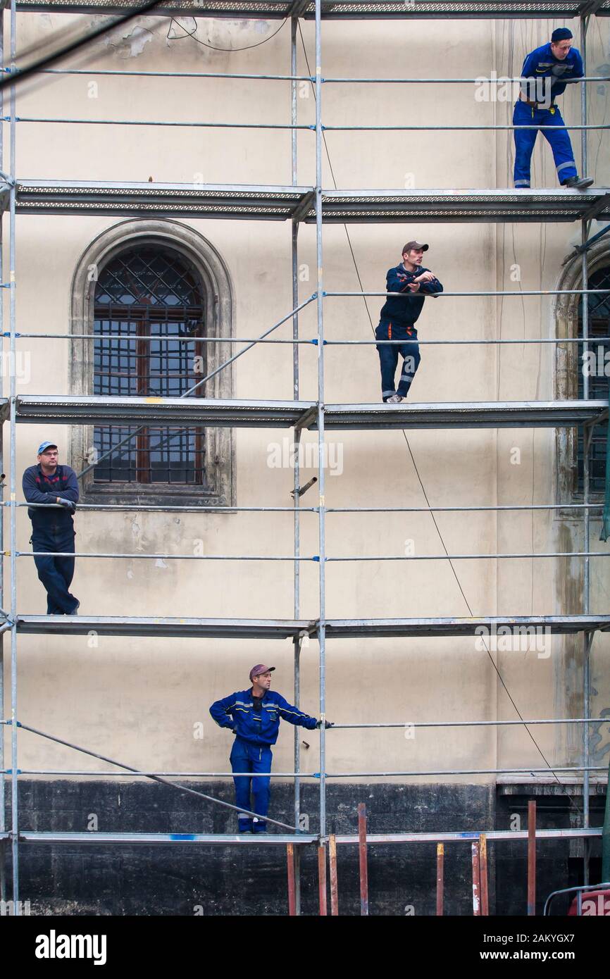 Die Arbeiter auf dem Gerüst warten darauf, dass die nächste Ladung passiert wird, während sie auf einem historischen Gebäude in Lemberg, Ukraine, errichten. Stockfoto