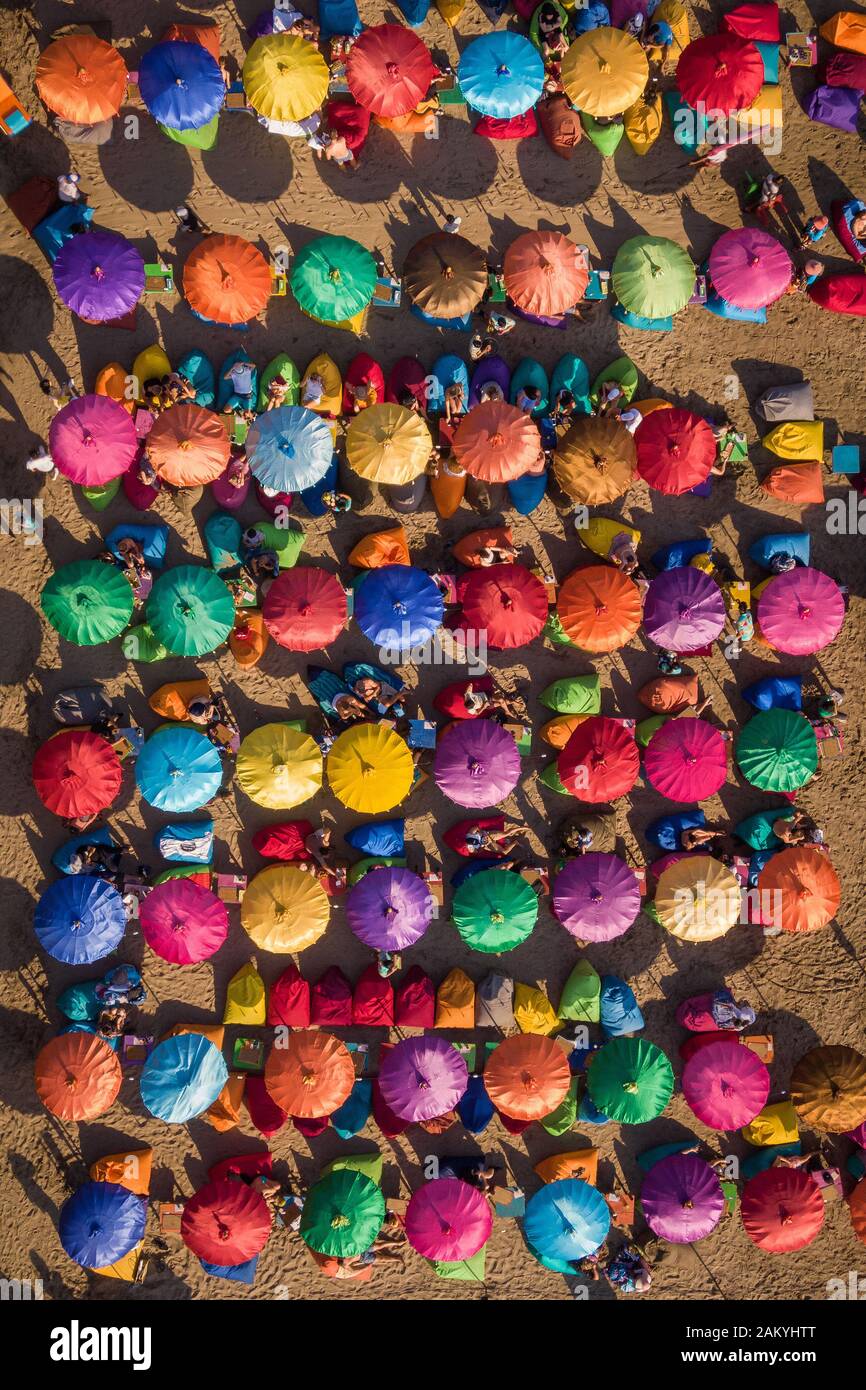 Top-down-Luftbild mit farbenfrohen Sonnenschirmen am berühmten Seminyak-Strand in Bali, Indonesien. Stockfoto