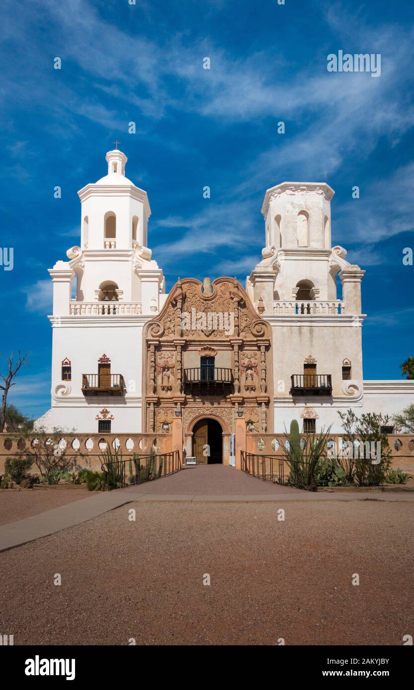 Frontalschuss der Mission von San Xavier del Bac in Tucson mit Kirchturm und historischem Eingang. Sonniger Tagesschuss, blauer Himmel mit wenigen Wolken. Kein Peop Stockfoto