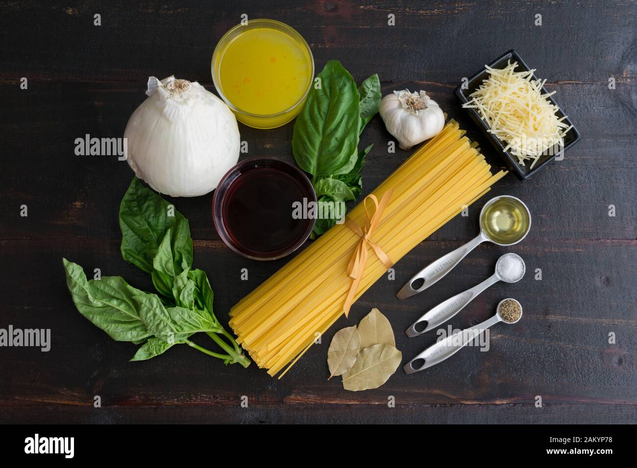 Zutaten für Rotweinpasta: Ungekochte Lingine, Basilikumsprigs und andere Zutaten, die zur Herstellung von Pasta in Rotweinsauce verwendet werden Stockfoto