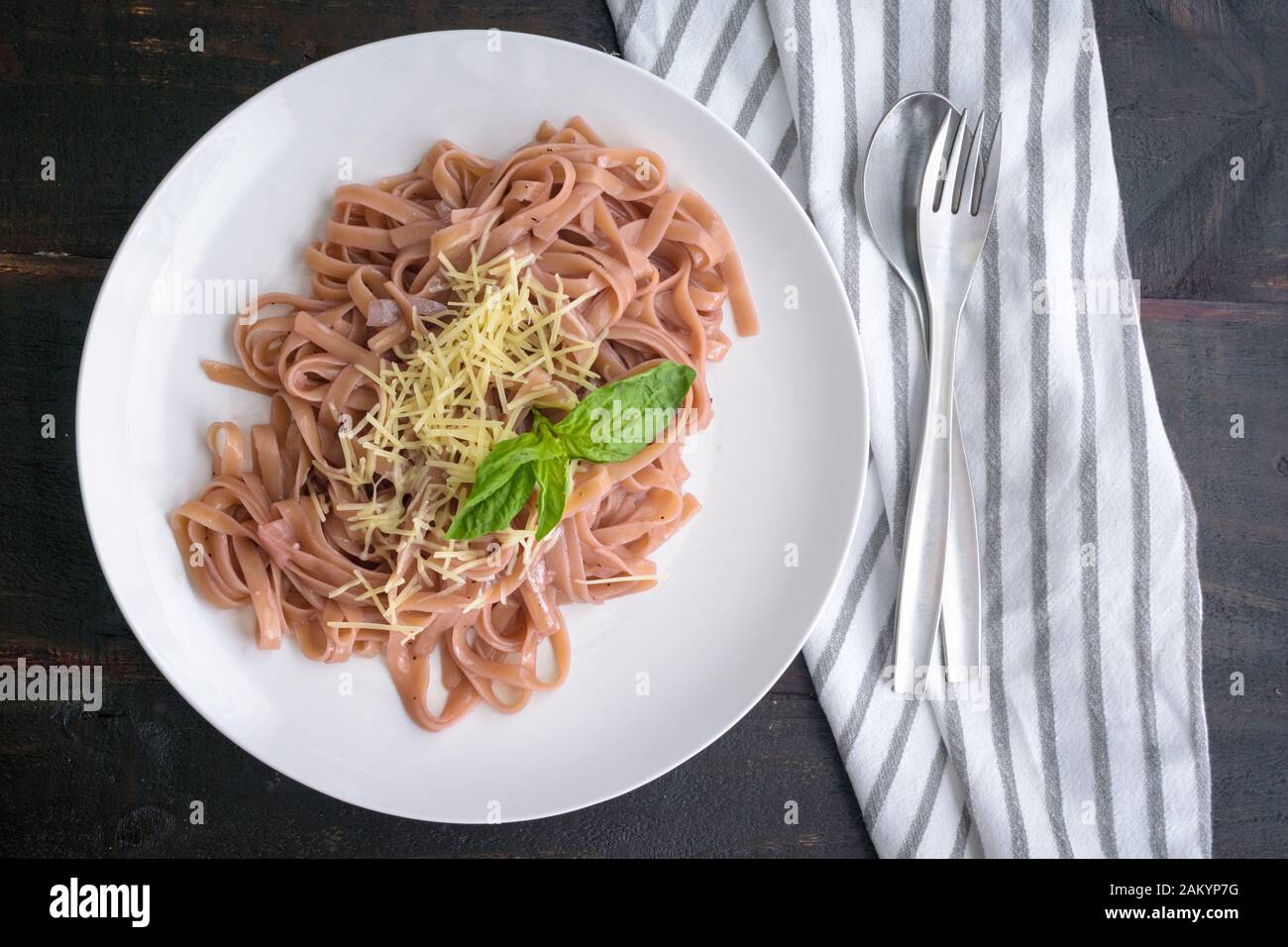 Pasta in Rotweinsauce: Lingine mit Rotweinsauce mit geschreddertem Parmesankäse und einer Basilikumgarnierung Stockfoto