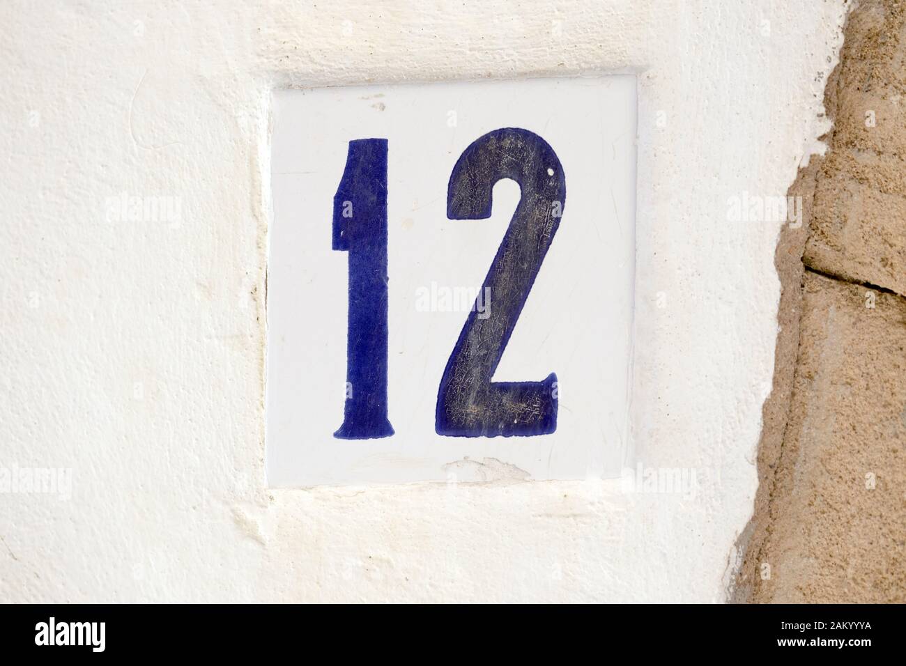 Blaue Hausnummer 12 an einer weißen Wand Stockfoto