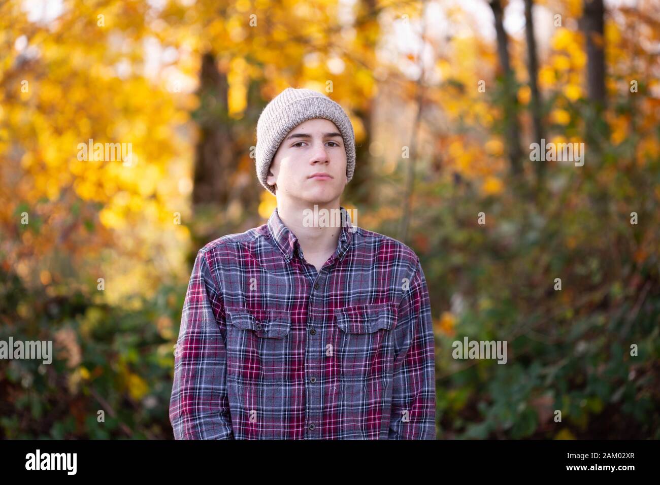 Serious teen junge in Beanie und karierte Hemd im Freien starrt auf Kamera Stockfoto