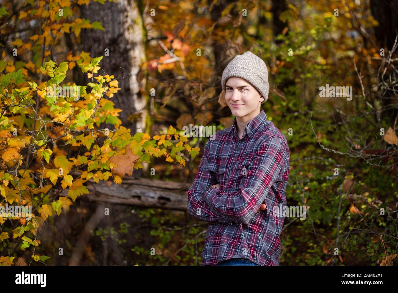 Lächelnder Teenager mit gekreuzten Armen steht in Wäldern, pazifischer Nordwesten Stockfoto