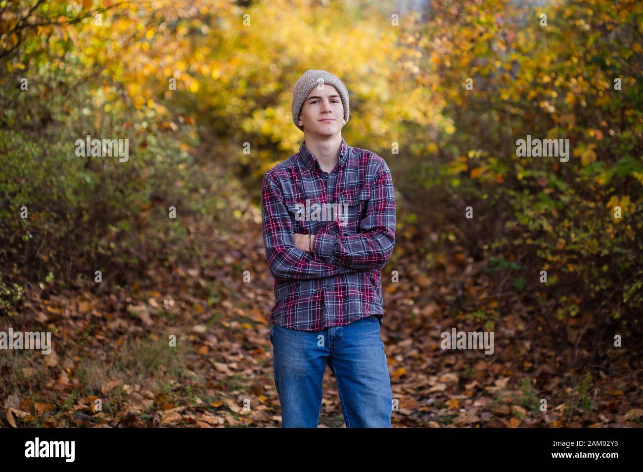 Zuversichtlich Teenager Junge steht in Wäldern allein mit gekreuzten Armen. Stockfoto