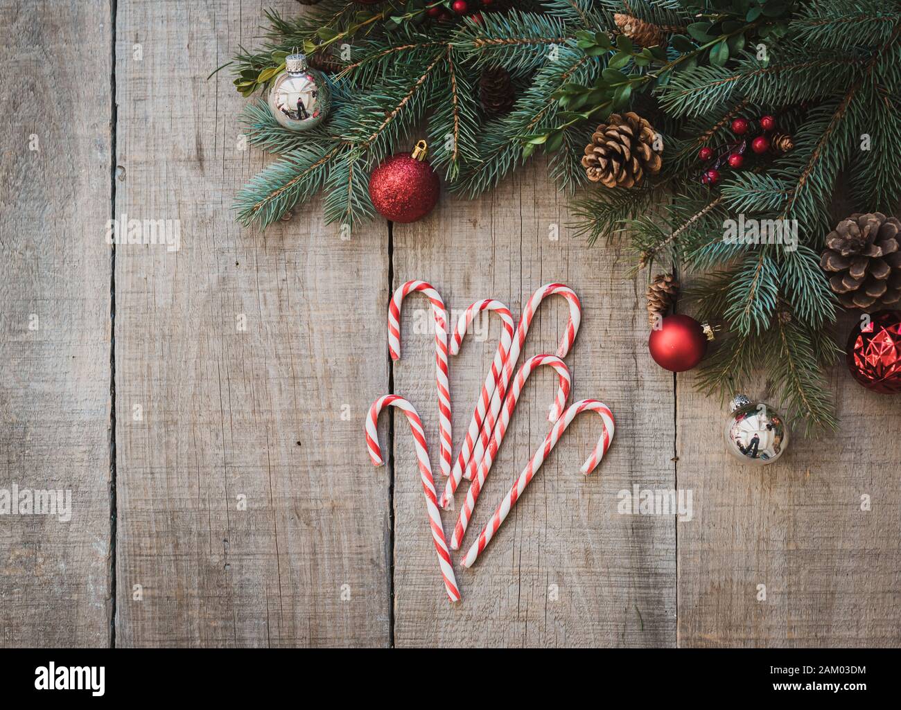 Zuckerstangen auf verwittertem Holztisch mit weihnachtlicher Einrichtung von oben. Stockfoto