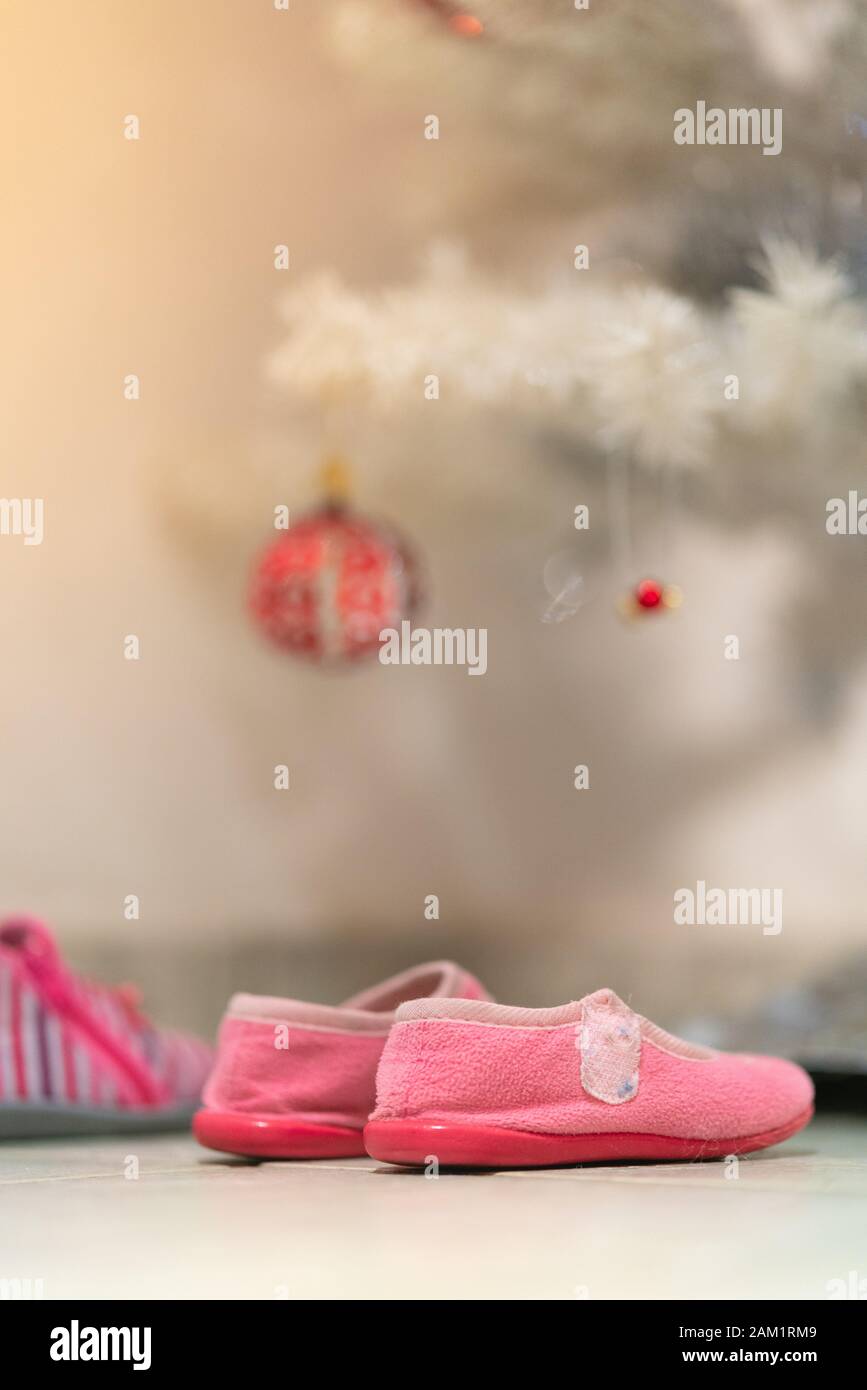 Kleine Mädchen Schuhe unter dem Weihnachtsbaum, um Geschenke zu erhalten: Französisches Konzept der Traditionen der Weihnachtstage Stockfoto