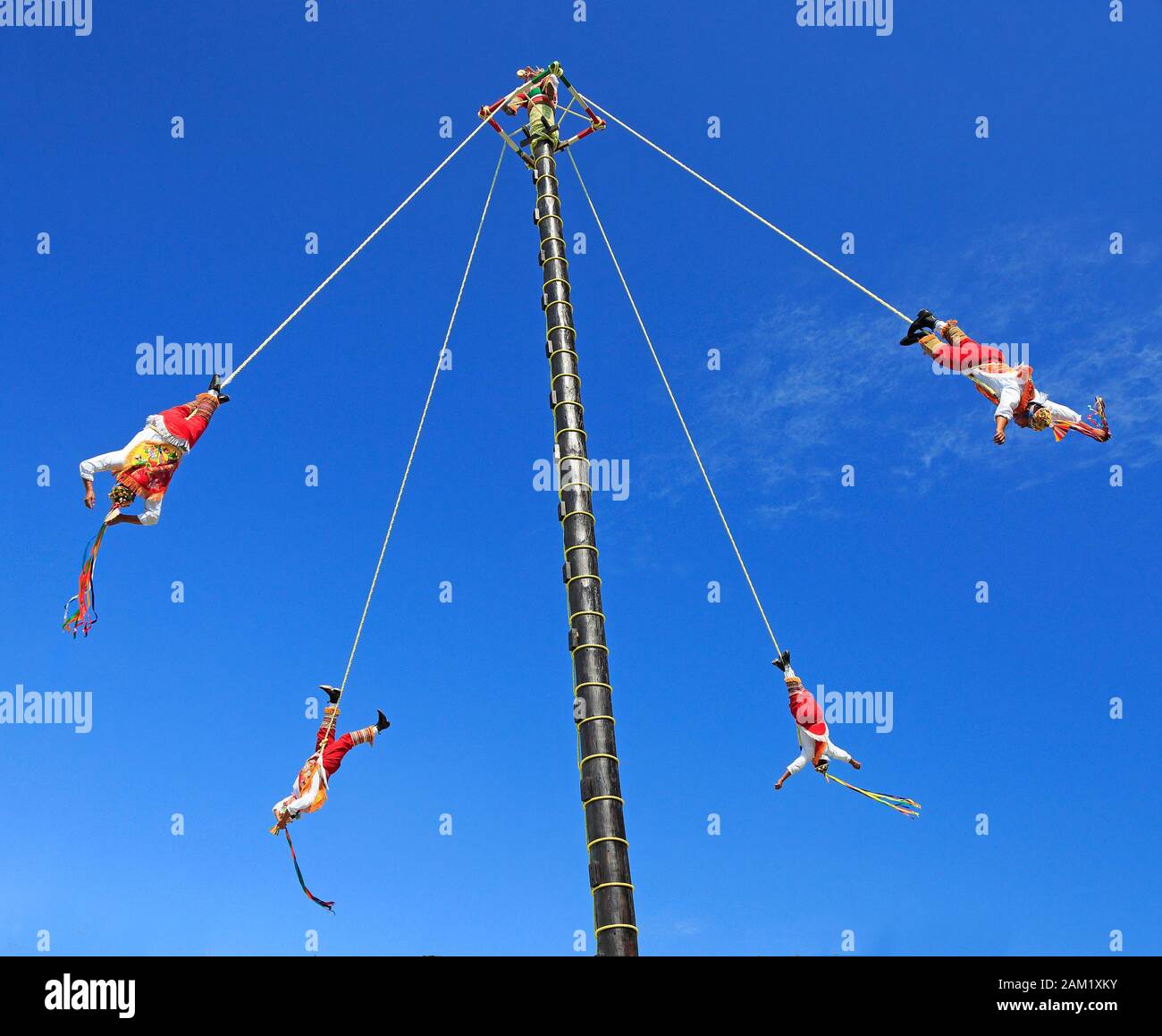 : Die Voladores oder Flyer Performance. Sie klettern einen sehr hohen Pfosten an ihrer Taille hoch, um Seile zu ziehen, die um den Pfosten gewickelt sind, und springen dann ab, wobei sie anmutig fliegen Stockfoto