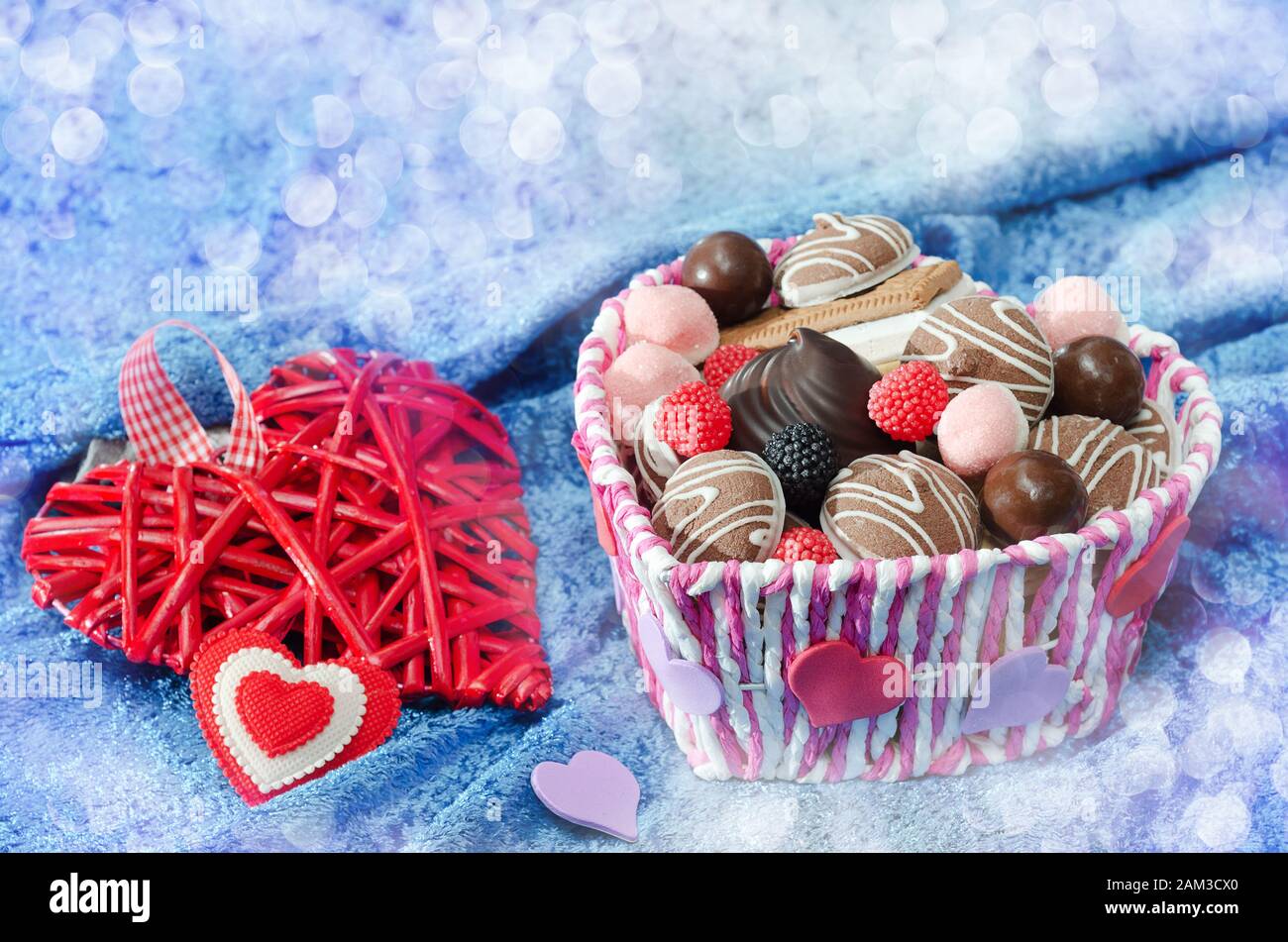 Süßigkeiten und dekorative Herzen am Valentinstag auf blauem Samtleinwand und Bokeh Stockfoto