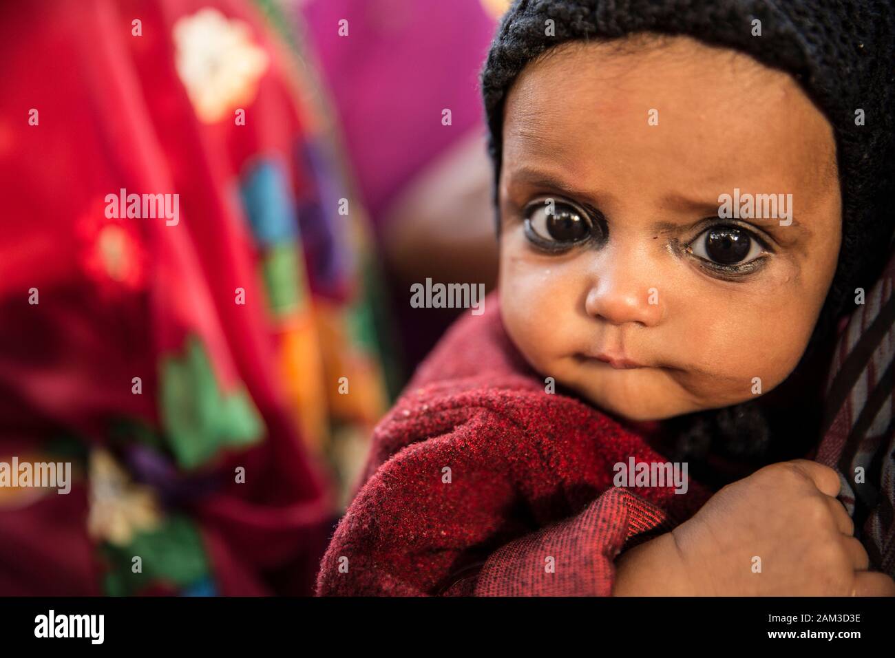 Kleines Baby, das das Lathmar Holi Festival in einem Dorf in der Nähe von Mathura besucht. Mathura, Indien Stockfoto