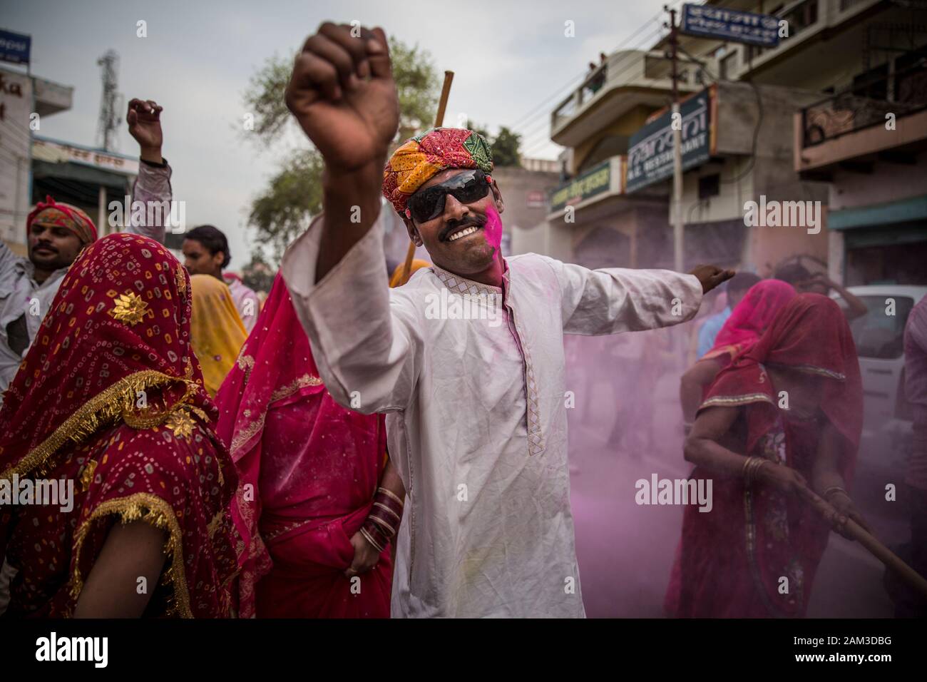 Mann tanzt, während Frauen Lathmar Holi in Mathura spielen. Indien Stockfoto