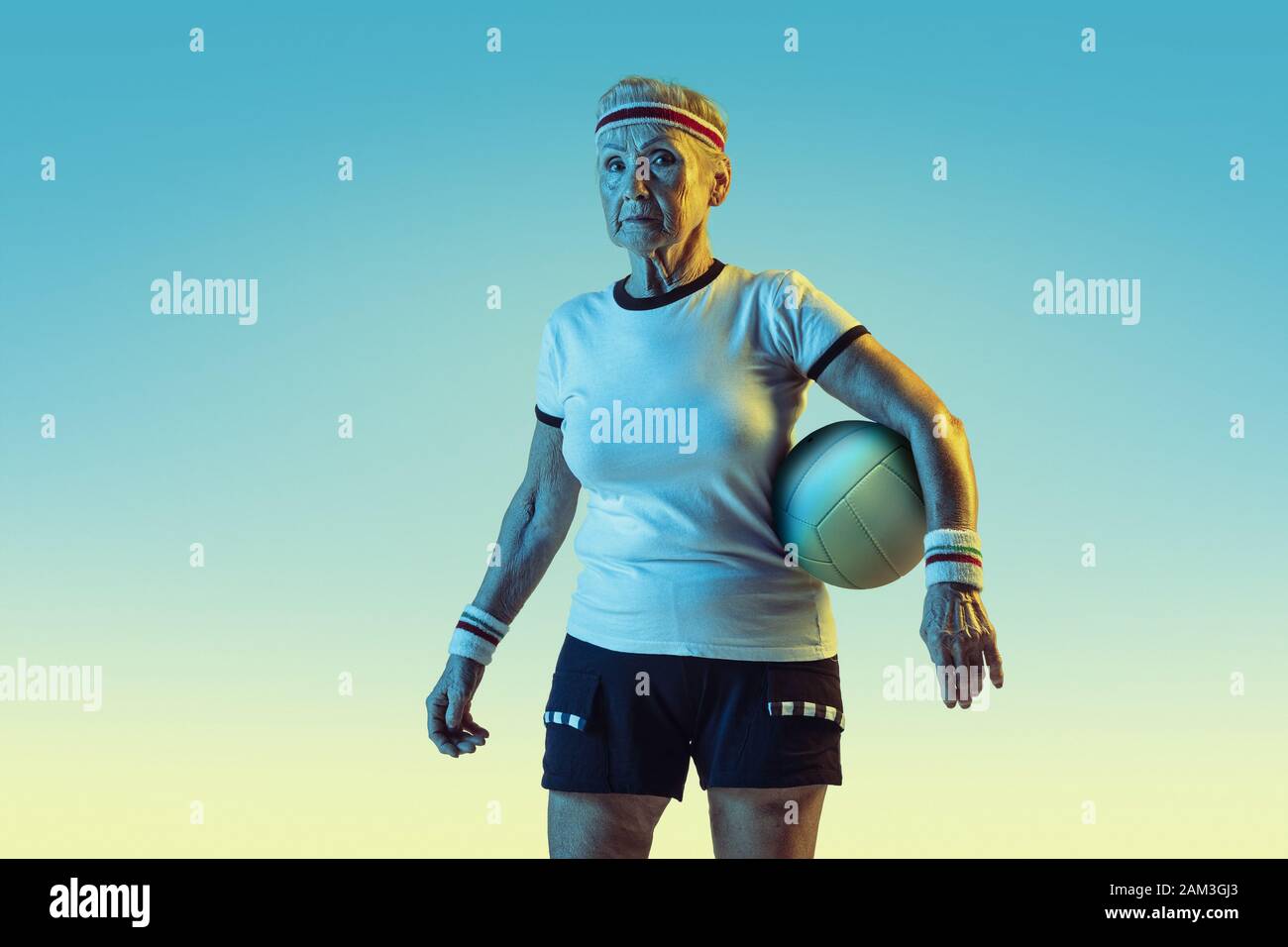 Ältere Frau in Sportbekleidung Ausbildung im Volleyball auf  Verlaufshintergrund, Neonlicht. Weibliche Model in der großen Form bleibt  aktiv. Konzept für Sport, Aktivität, Bewegung, Wohlbefinden, Vertrauen.  Copyspace Stockfotografie - Alamy