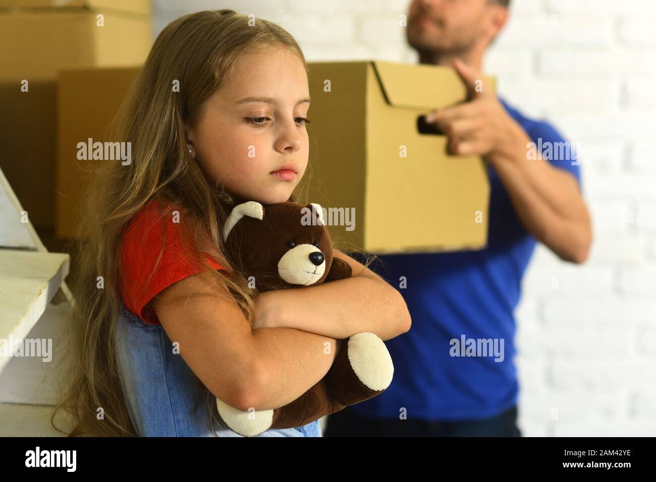 Kind Und Kerl Bewegen Sich Ein Oder Ziehen Aus Tochter Umarmt Teddybar Und Vater Halt Kiste Madchen Mit Traurigem Gesicht Und Mann Im Hintergrund Entscharft Neues Haus Einsamkeit Und Familienkonzept Stockfotografie