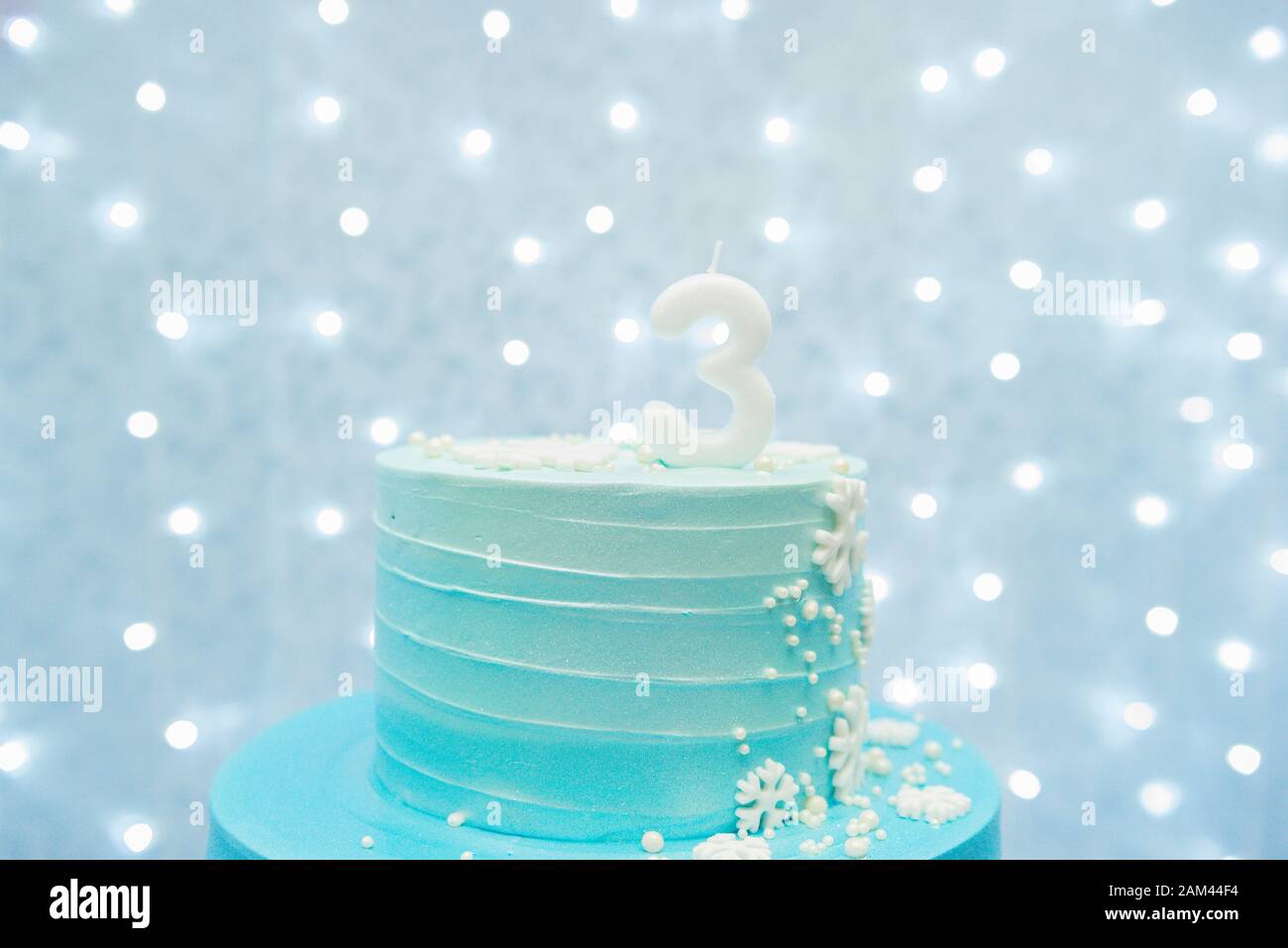 Zweistufiger Kuchen auf blauem Hintergrund mit unfokussierten Lichtern Stockfoto