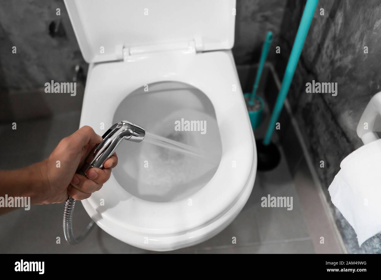 Mit Hilfe von Bidet mit einem weißen wc dusche. Bidet Dusche in männlicher Hand für die Verwendung mit einem weißen wc Schüssel. Stockfoto