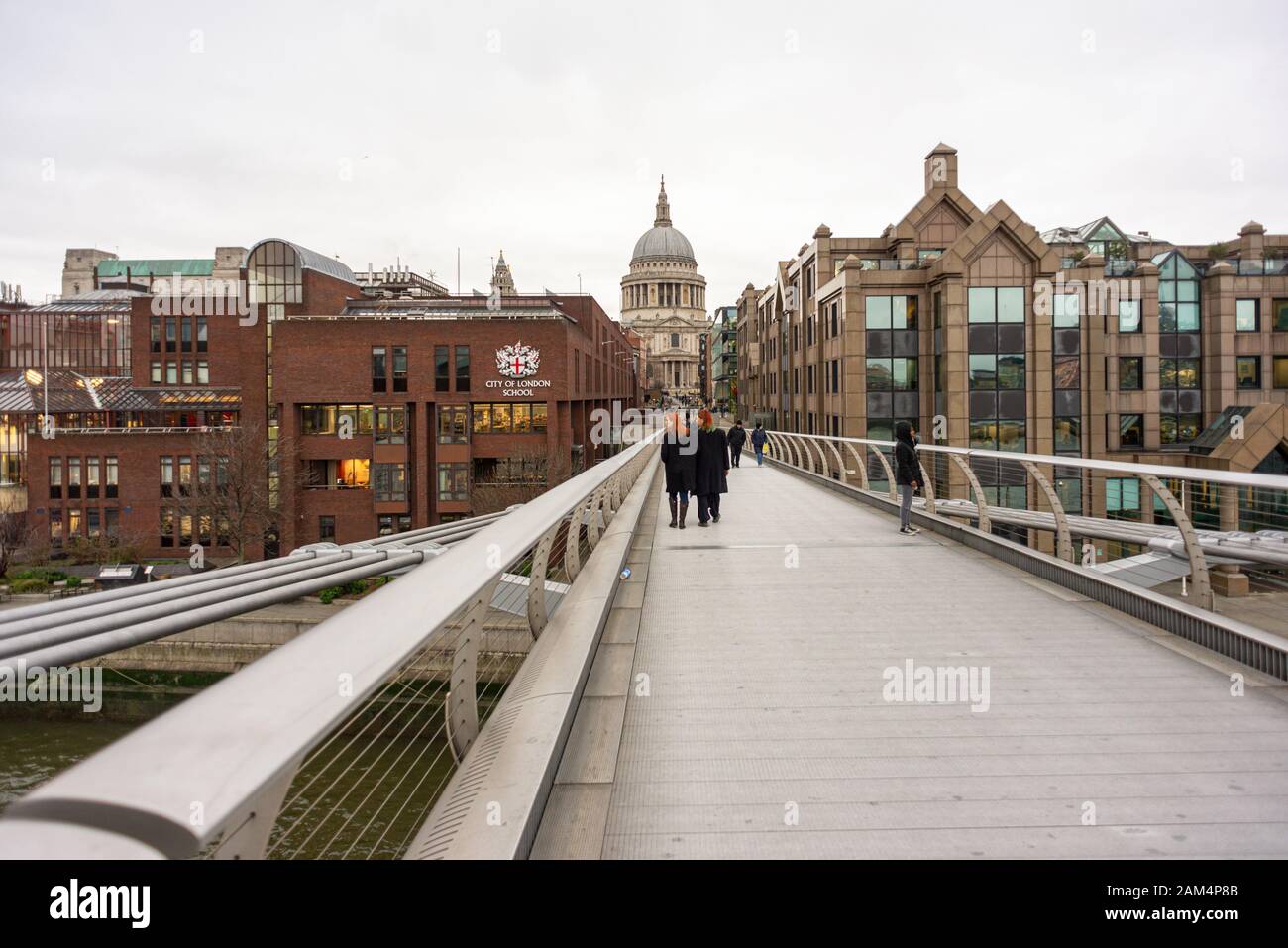 Menschen auf der Millennium Bridge in der Nähe der City of London School und der St Paul's Cathedral, London im Winter Stockfoto