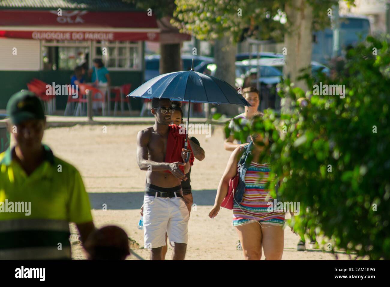 Coimbra, PORTUGAL - 16. Juli 2016 - EIN Mann verwendet einen Regenschirm, um sich während einer Hitzewelle in Coimbra Portugal kühl zu halten Stockfoto