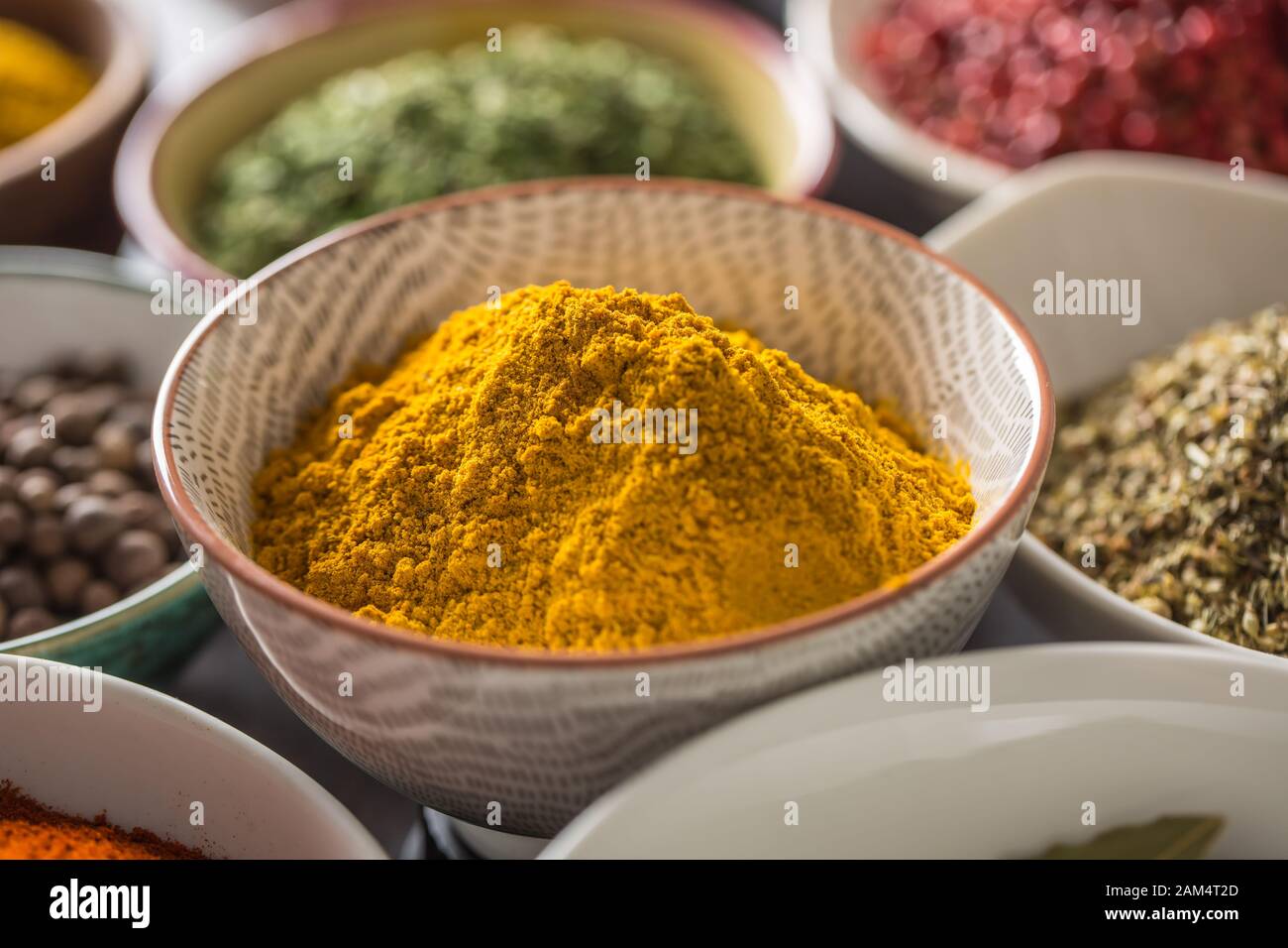 Curry und verschiedene Gewürze und Kräuter in Schüsseln Stockfoto