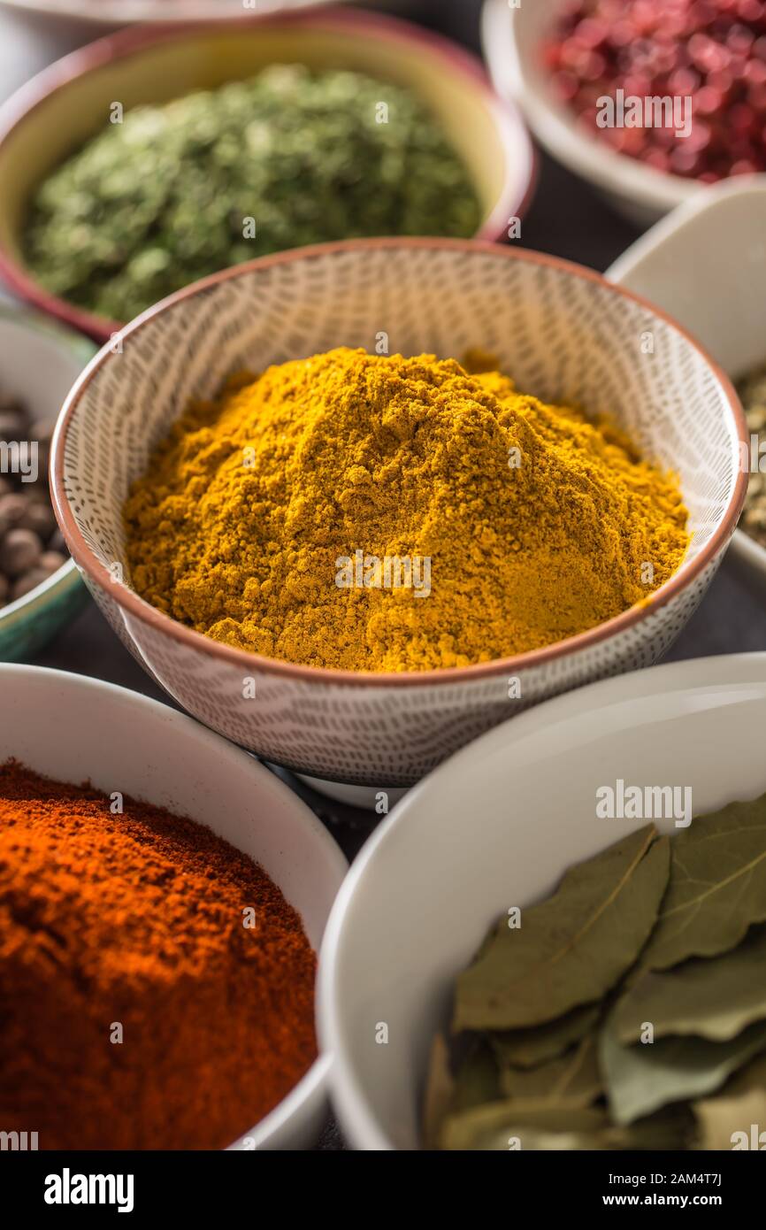 Curry und verschiedene Gewürze und Kräuter in Schüsseln Stockfoto