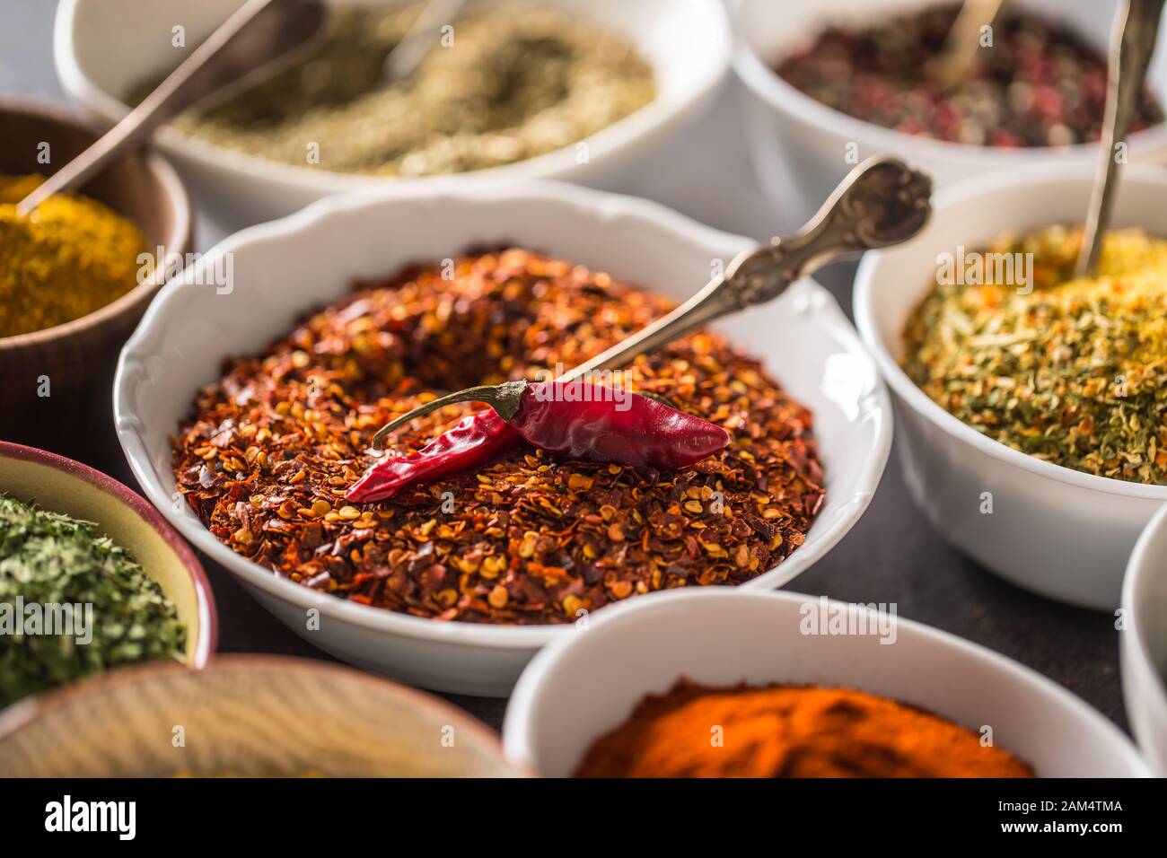 Gemahlene Chili und verschiedene Gewürze und Kräuter in Schüsseln Stockfoto