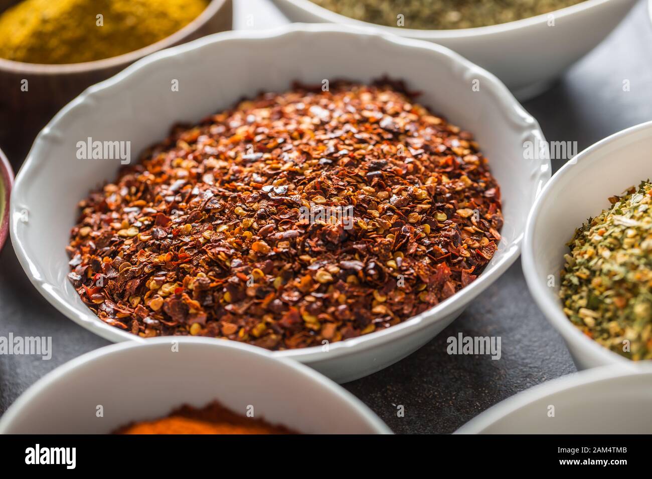 Gemahlene Chili und verschiedene Gewürze und Kräuter in Schüsseln Stockfoto