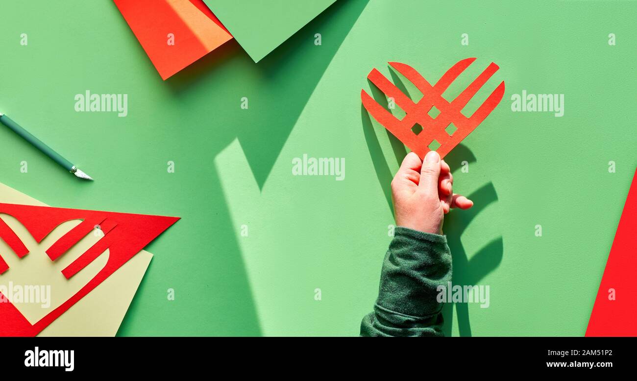 Creative Paper Flach, Panoramablick auf die Komposition. Geben Dienstag Konzept. Geometrische Design mit Streifen Herz in der Hand, lange Schatten. Givingtuesday ist ein s Stockfoto