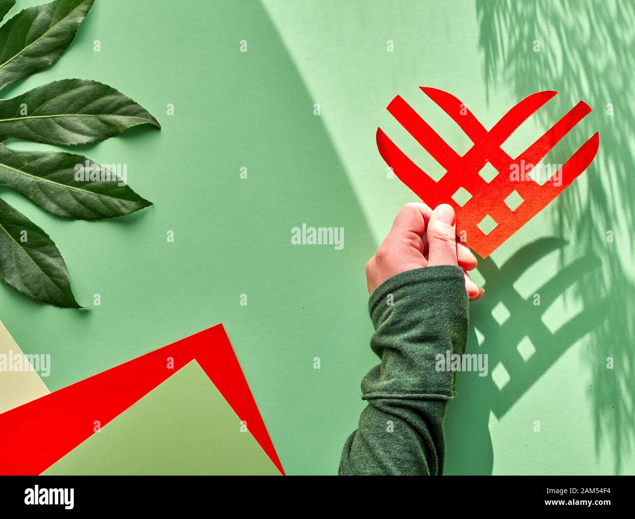 Creative Paper legen, Ansicht von oben, die Dienstag Konzept. Geometrische Papier flach Layout mit Streifen Herz in der Hand, lange Schatten. Givingtuesday ist eco Freund Stockfoto