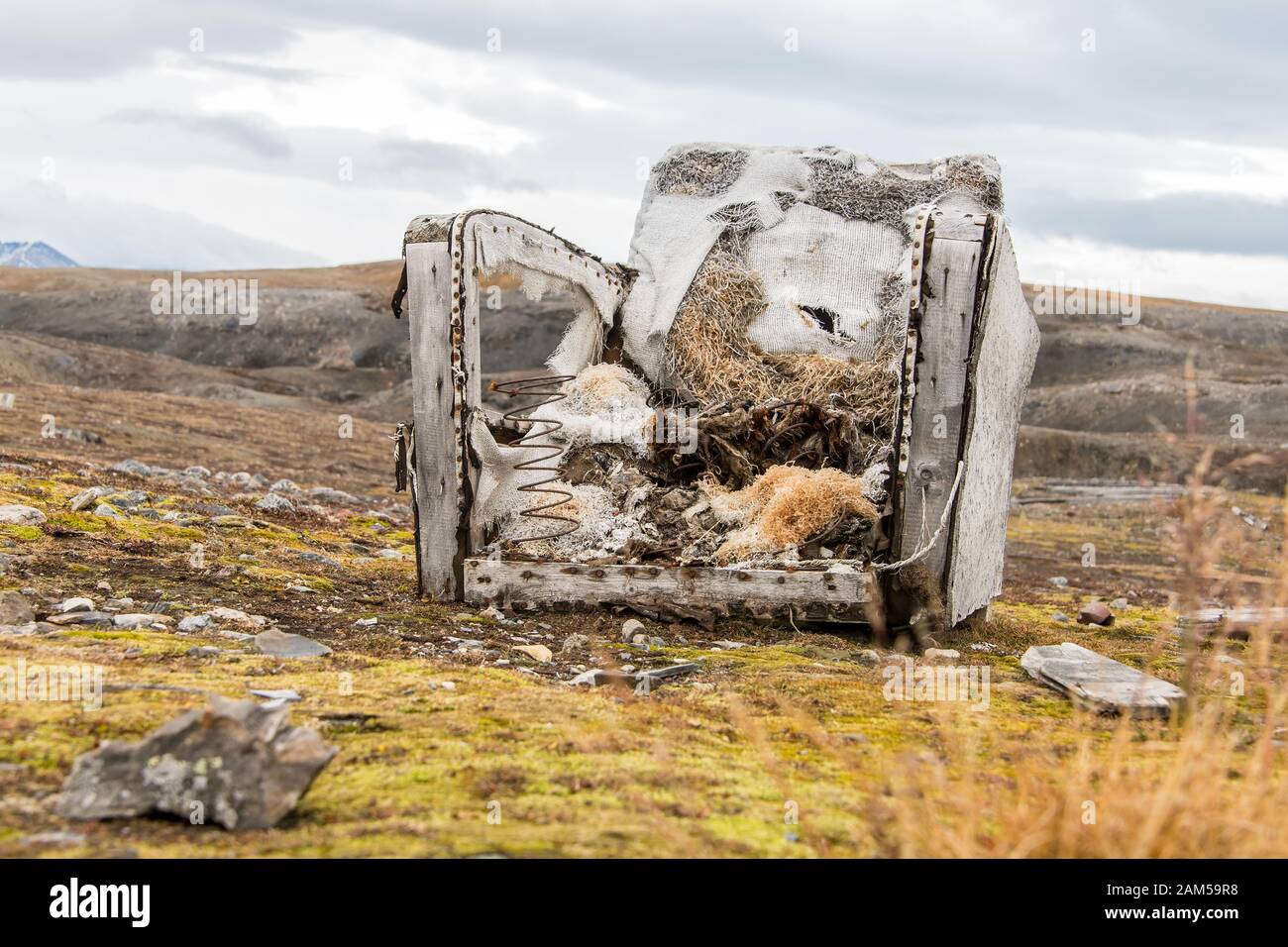 Sehr unbequemer gebrochener Sessel auf der Wiese - Müll in der Umgebung Stockfoto