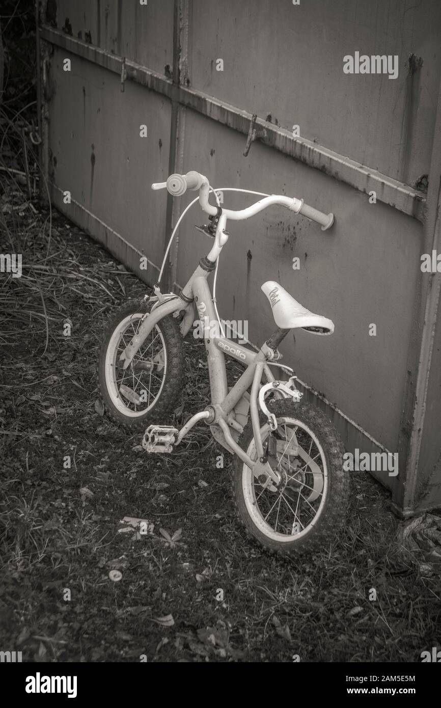 Balck und Weiß des Kinderfahrrads sind neben einem Recycling-Müllcontainer nicht mehr da. Metaphernrecycling, Kindheitserinnerungen, Fahrradfahren lernen. Stockfoto