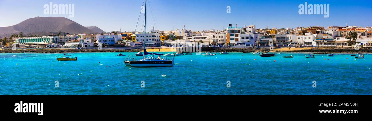 Wunderschönes Dorf in Corralejo, Blick auf türkisfarbenes Meer, Berge und traditionelle Fischerboote, Fuerteventura, Spanien. Stockfoto