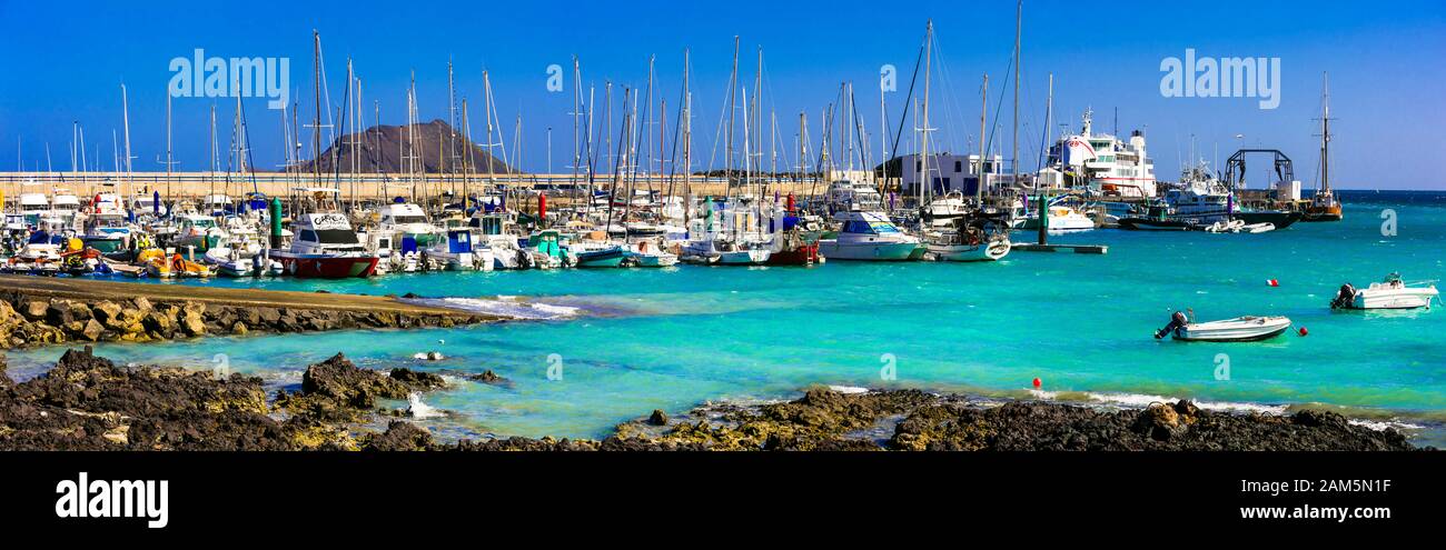 Wunderschönes Dorf in Corralejo, Blick auf traditionelle Fischerboote, türkisfarbenes Meer und Berge, Insel Fuerteventura, Spanien. Stockfoto